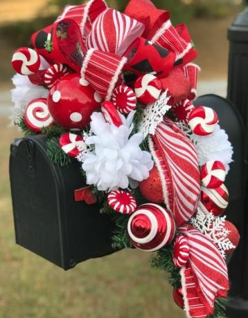 svart brevlåda med röda och vita prickade och randiga julbollar, band och dekorativa godis med vita blommor