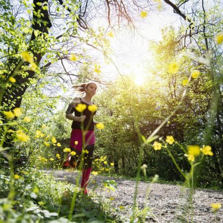 ung sportig kvinna joggar genom skogen