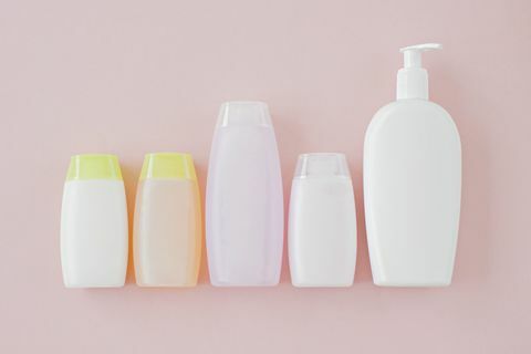 Omärktade flaskor med skönhetsmedel på en rosa bakgrund