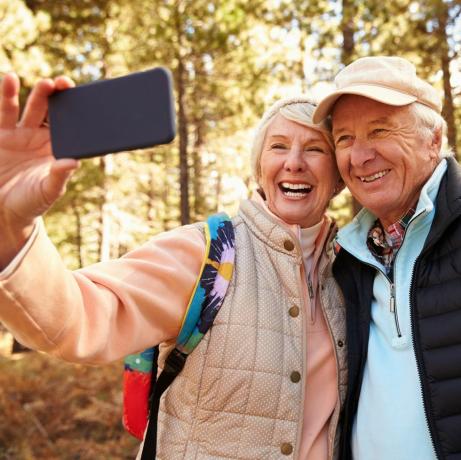 Äldre par på vandring i en skog som tar en selfie