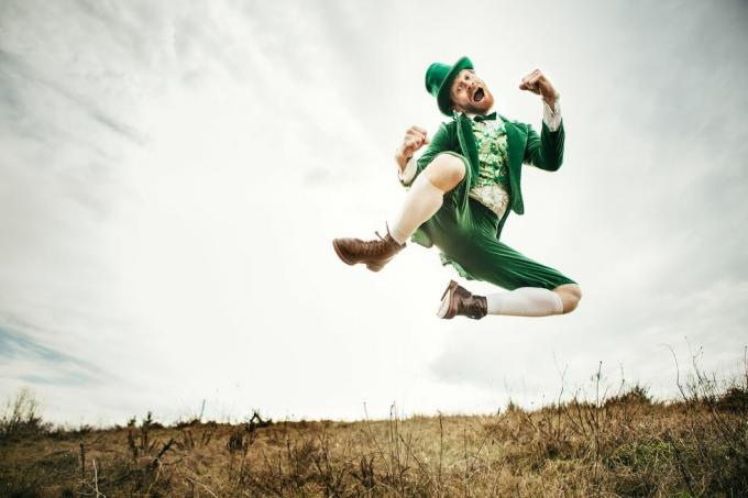en stereotyp irländsk karaktär redo för Saint Patricks day hoppar och dansar i ett öppet fält av irländsk landsbygd kopieringsutrymme i himlen och gräset