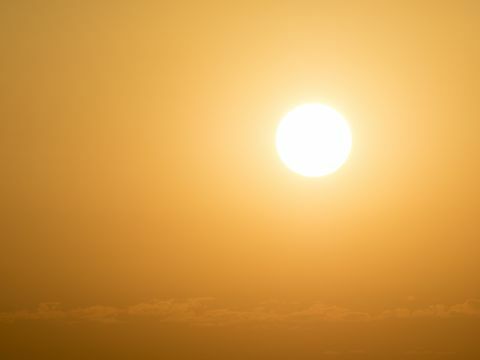 Glödande sol för full ram vid solnedgången med en orange och gul himmel