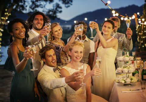 Gifta sig gäster som rostar med champagne under bröllopsmottagning i trädgården