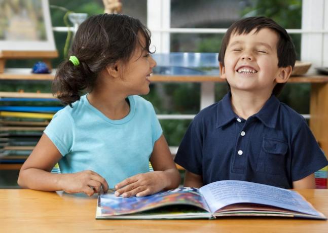 två skrattande barn som njuter av en bok i skolan