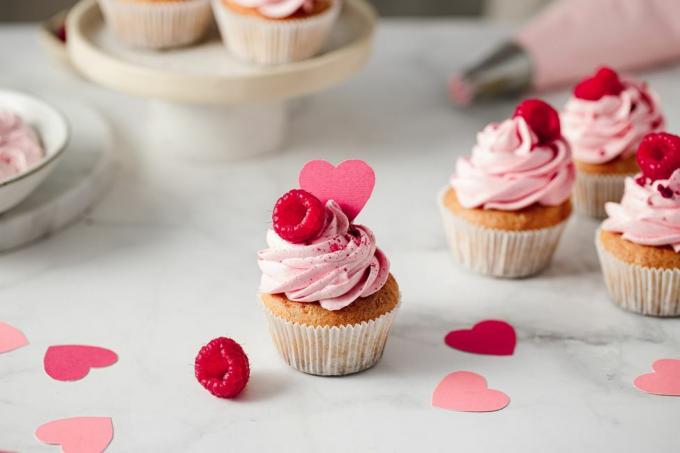 nygjorda hallon cupcakes på köksbänken läckra rosa cupcakes med hallon och papper hjärta topping