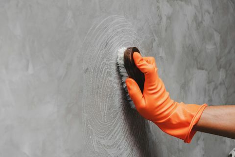 Beskuren hand av mannen som rengör grå vägg