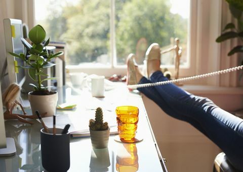 Kvinna som talar i telefon på hemmakontoret - bara hennes fötter och ben visas