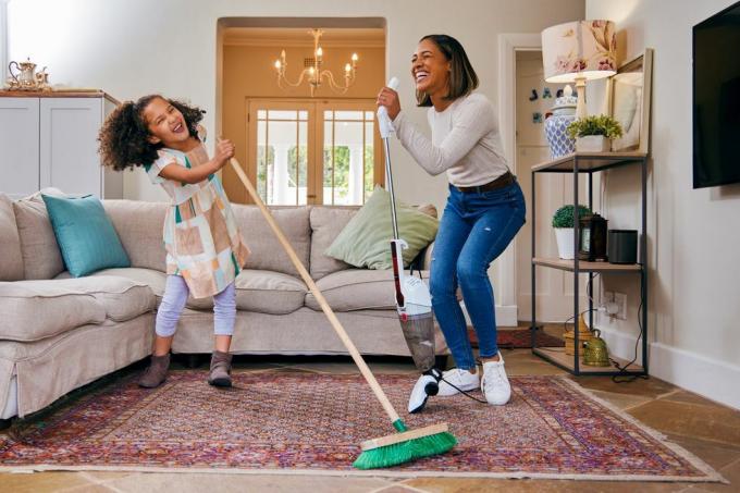 bild av en mor och dotter som har roligt medan de städar vardagsrummet