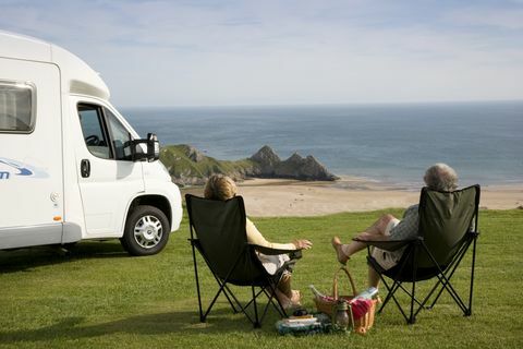 Ett par med en picknick som kopplar av i sina stolar bredvid sin husbil som tycker om utsikten över Three Cliffs Bay på Gower-halvön i Wales., Three Cliffs Bay, Swansea, Wales.