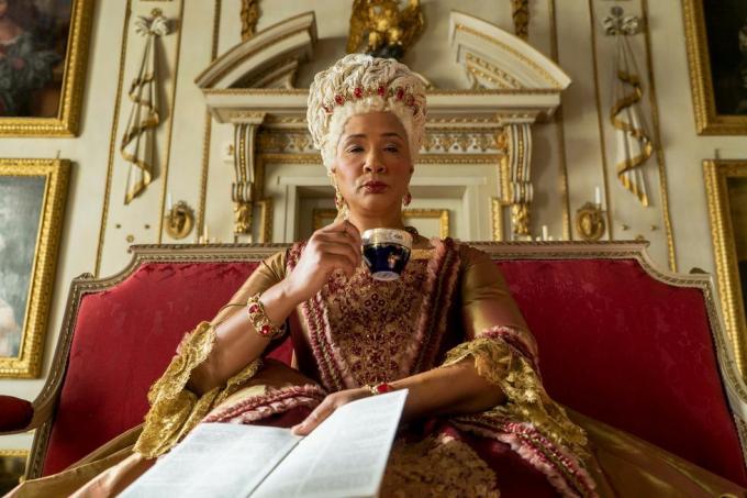 bridgerton golda rosheuvel som drottning charlotte sitter och dricker te i guld och ros klänning i avsnitt 105 av bridgerton