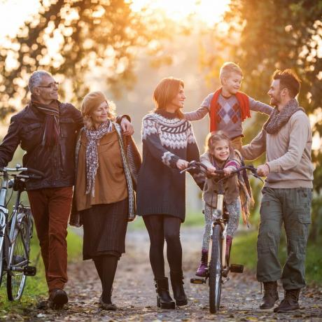 leende flergenerationsfamilj tar en promenad med cyklar i naturen och njuter av sin tid tillsammans