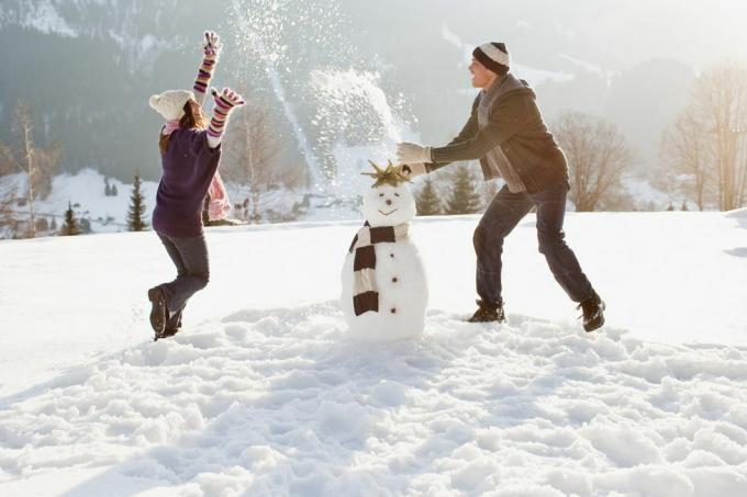 par gör snögubbe och spelar i snö