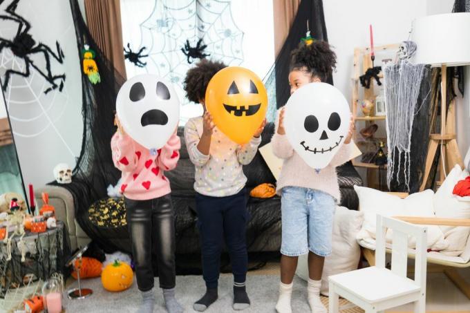 glada kaukasiska vita och afrikanska amerika barn får halloween fest i deras hus