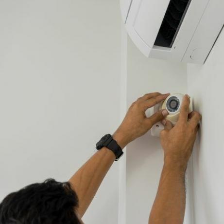 beskuren handman som installerar cctv på väggen hemma