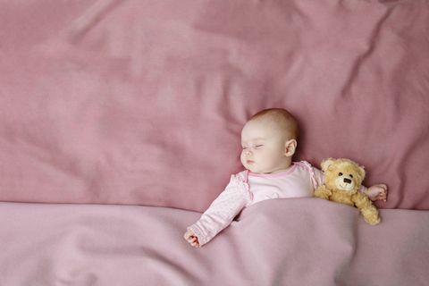 baby flicka i rosa säng