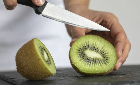 en kvinna som skär kiwi