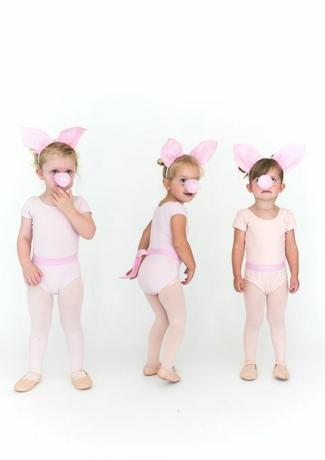 små flickor i rosa strumpbyxor och onesies med svinöron och grisnos