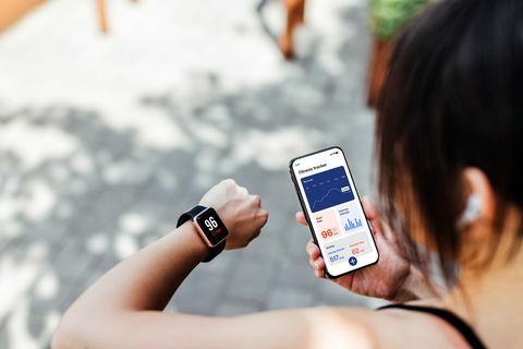 ung kvinna som använder fitness tracker app på smart klocka och smartphone