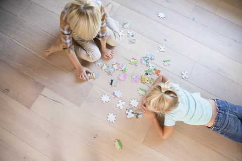 bror och syster som ligger på golvet hemma och spelar pussel