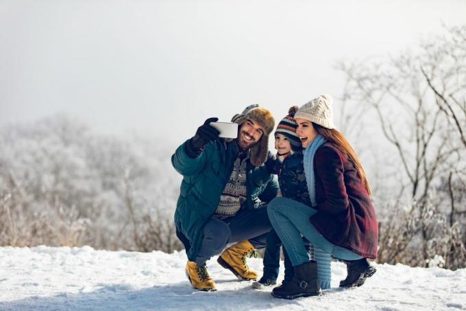 familj tar selfie på vinterdagen i den snöiga skogen