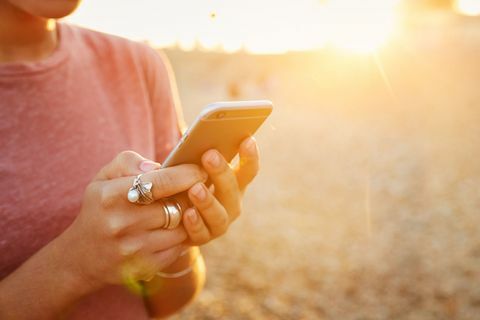 Kvinna som rymmer mobiltelefonen på stranden