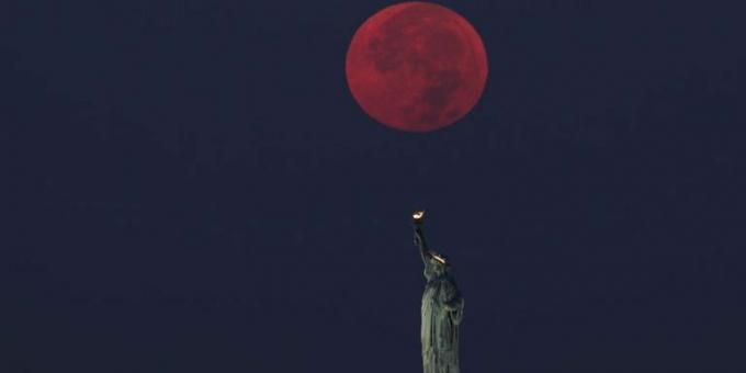 fullmånen går ner bakom frihetsgudinnan i new york city