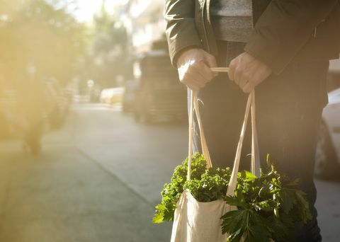 ung man som håller återanvändbar textil matkasse med gröna grönsaker