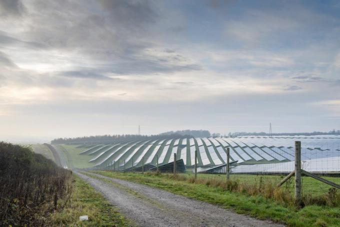 solenergiplats i hjärtat av den engelska landsbygden, inhägnad, med en smal grusväg som löper bredvid in i jordbruksmark