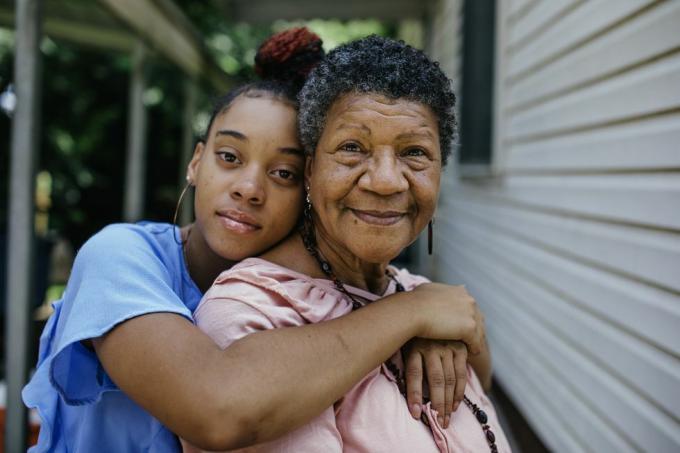 porträtt av svart mormor med tonårsbarnbarn som båda tittar in i kameran medlemmar av en svart medelklassfamilj i USA