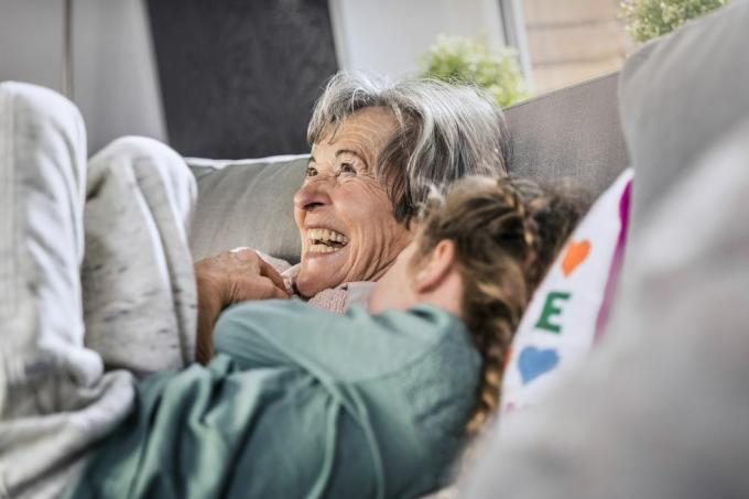 glad mormor liggande vid barnbarn på soffan hemma