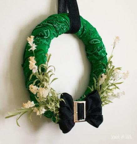 grön krans gjord av bandanas med en svart rosett med ett guldspänne längst ner, det är lövverkande lövverk som sticker ut ur fören